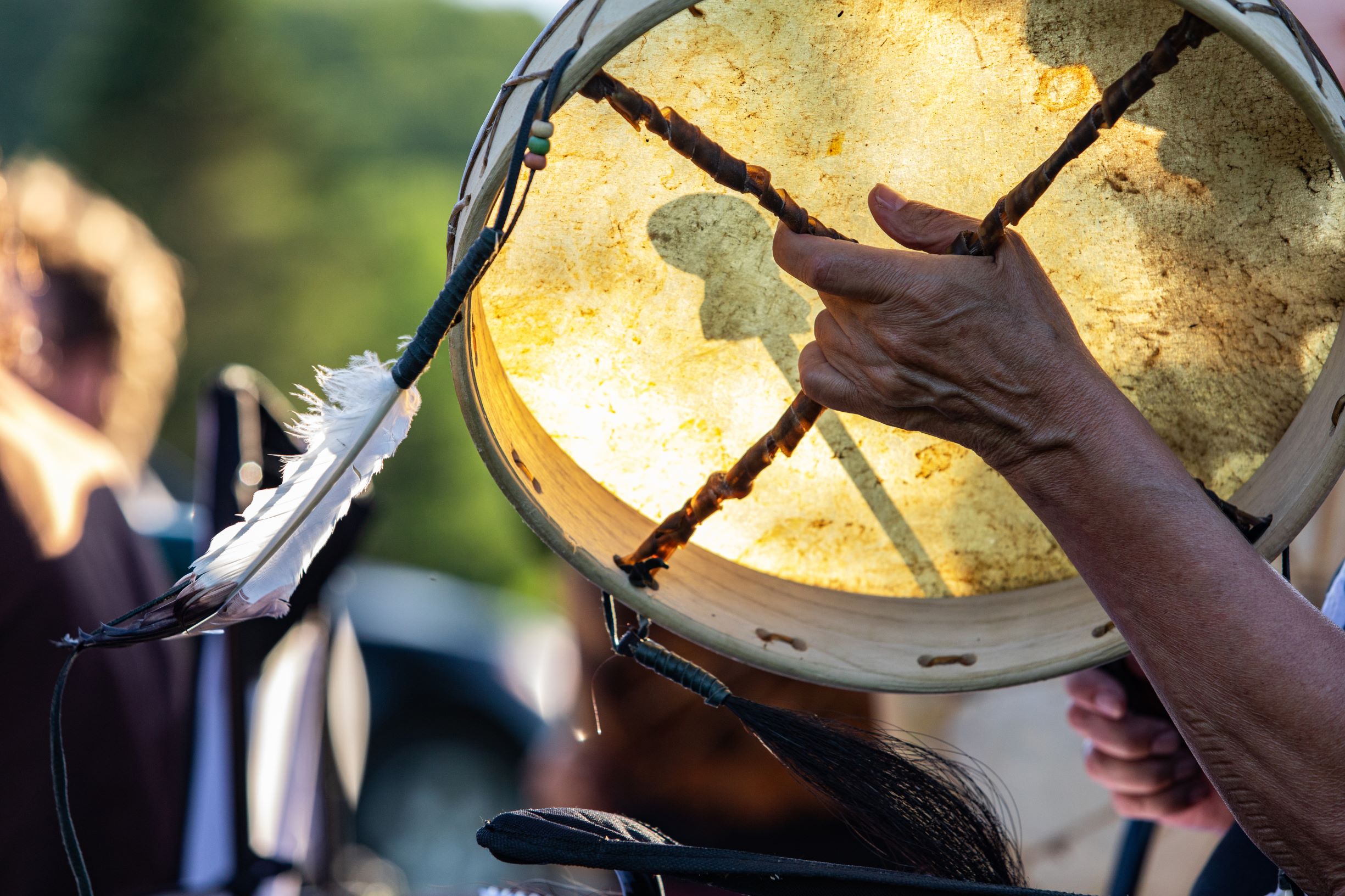 Indigenous drummer holding drum with feathers