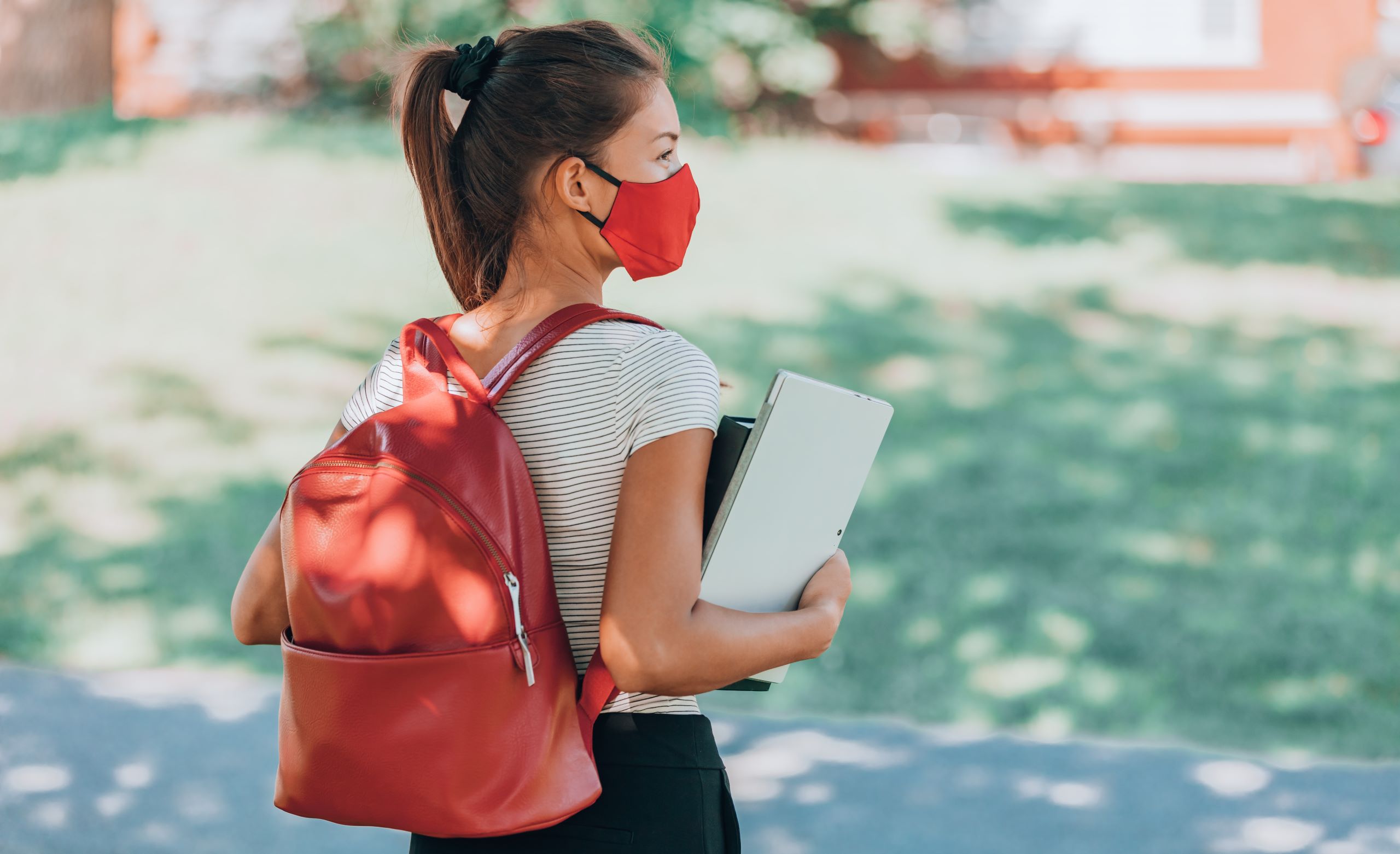 university student wearing backpack holding books