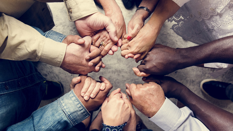 A group of people of various ages holding hands.