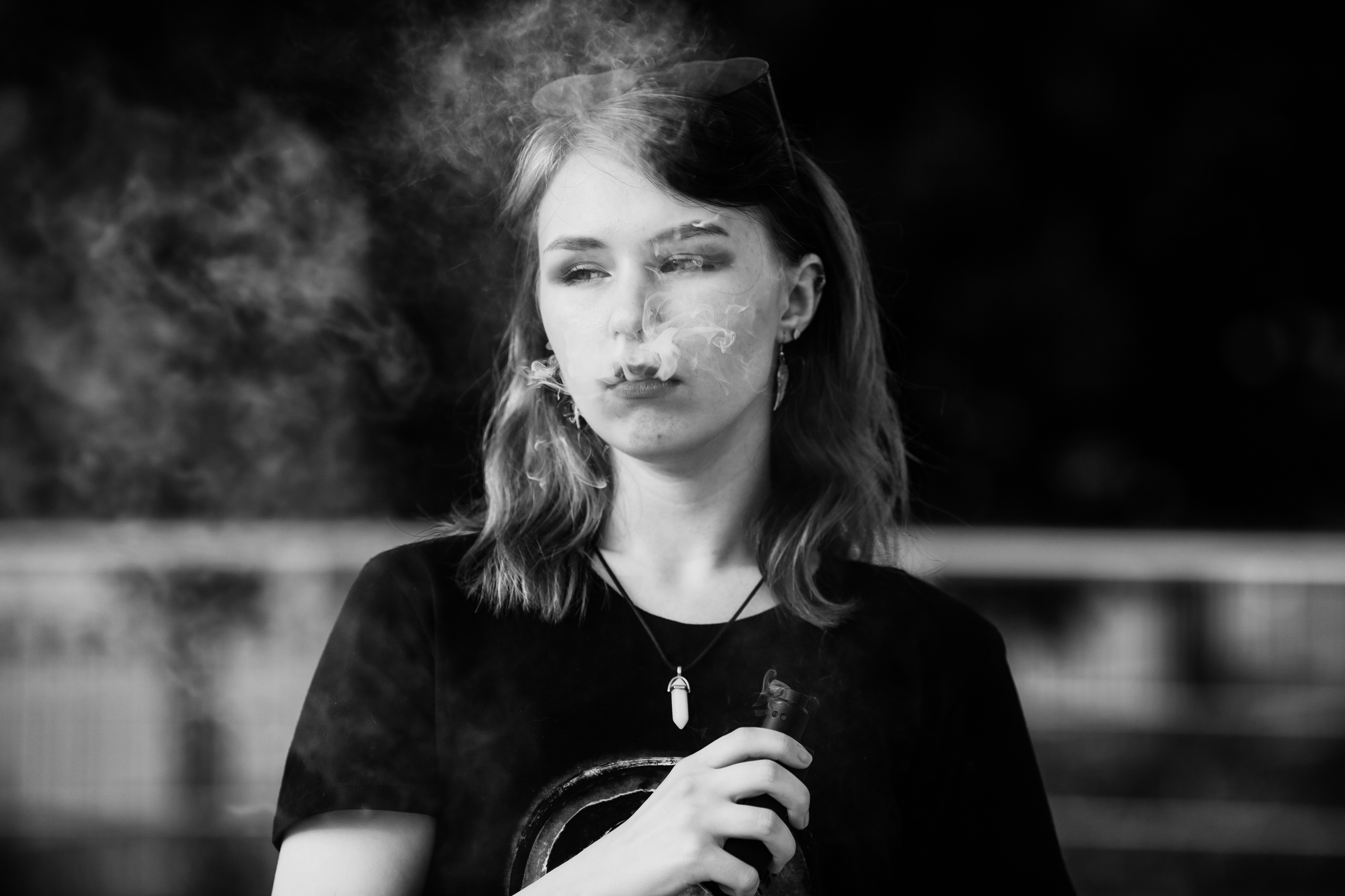 A black-and-white photo of teenaged girl vaping.
