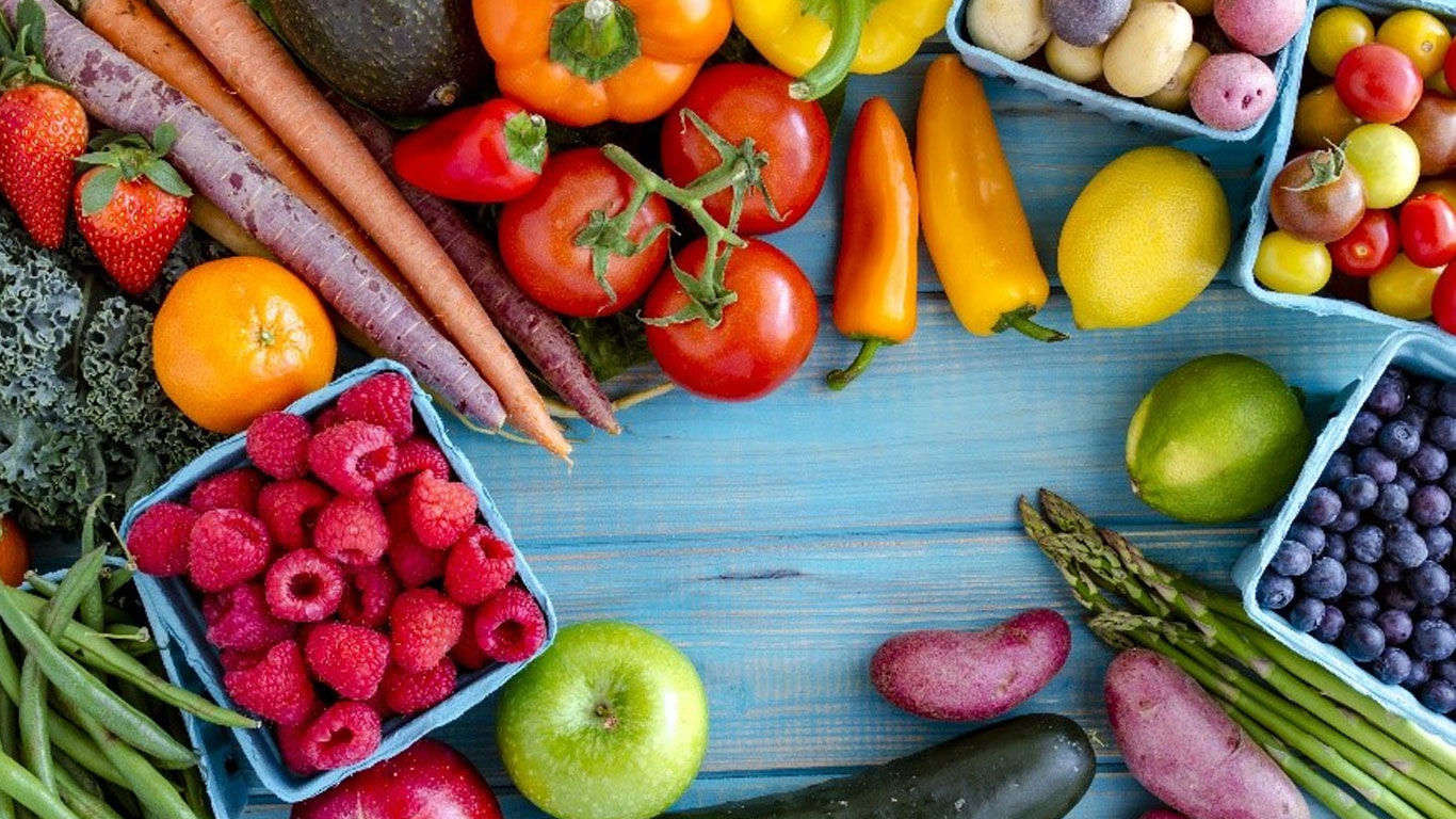 Légumes et fruits frais reposant sur une table bleue.