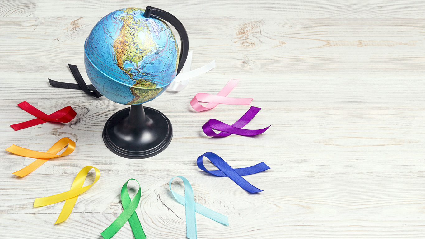 Un petit globe est entouré de rubans de sensibilisation au cancer de couleurs variées.