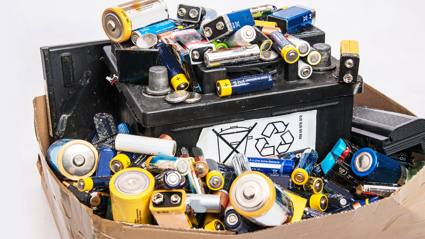 A pile of old household batteries and a car battery.