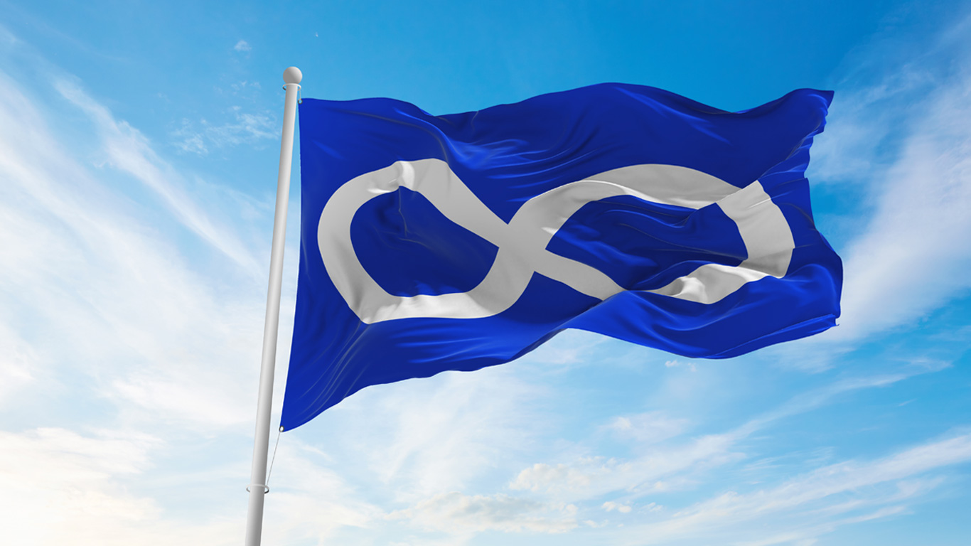 The Métis flag fluttering in a blue sky.