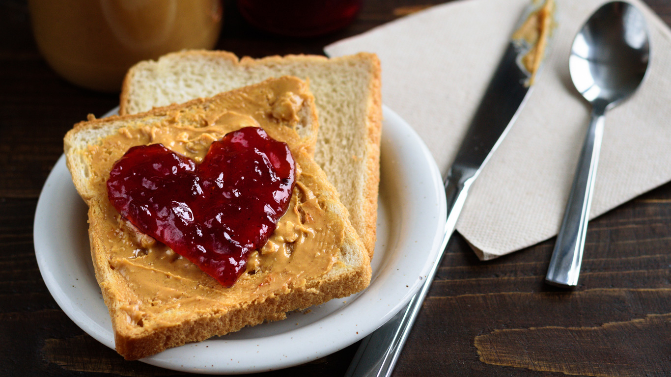 A peanut butter and strawberry jelly sandwich with the jelly shaped like a heart.