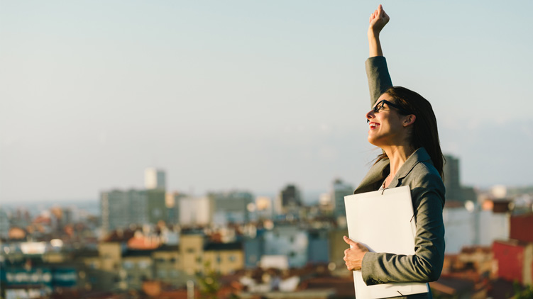 An executive woman raising her hand in joyful triumph. 