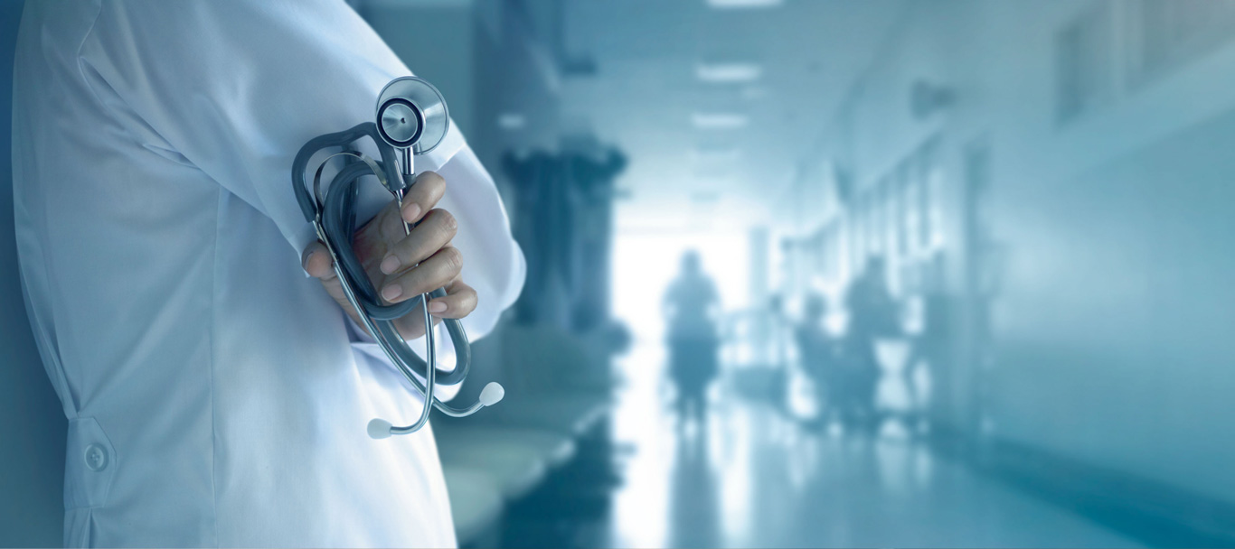 Un médecin en sarrau, stéthoscope à la main, sur fond d’hôpital.