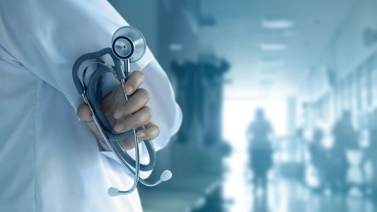 Un médecin en sarrau, stéthoscope à la main, sur fond d’hôpital.