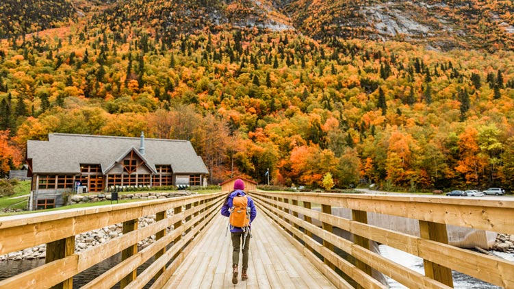 Une femme traversant un pont en bois dans la campagne québéciose.