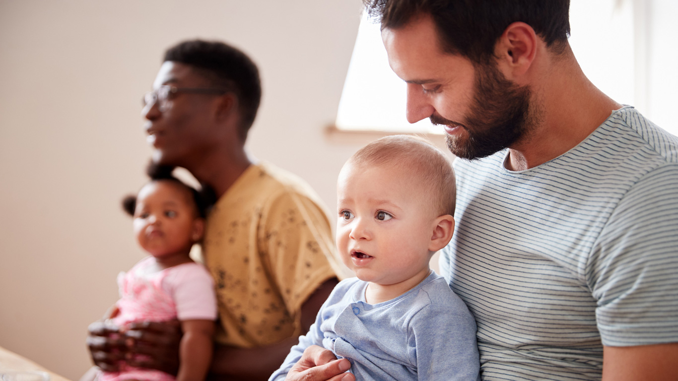 Two parents with babies meeting and talking around a table.