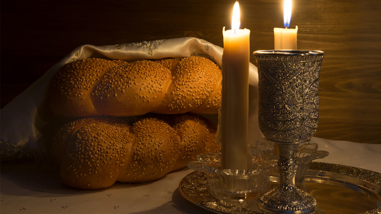 A Shabbat shalom wine, challahs and candles for a traditional Jewish Sabbath ritual.
