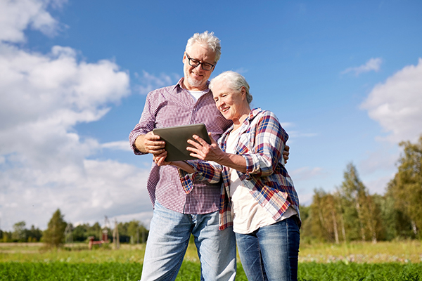Un homme et une femme regardent une tablette dans un champ. 
