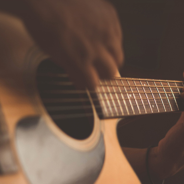 Gros plan sur des mains jouant de la guitare. 