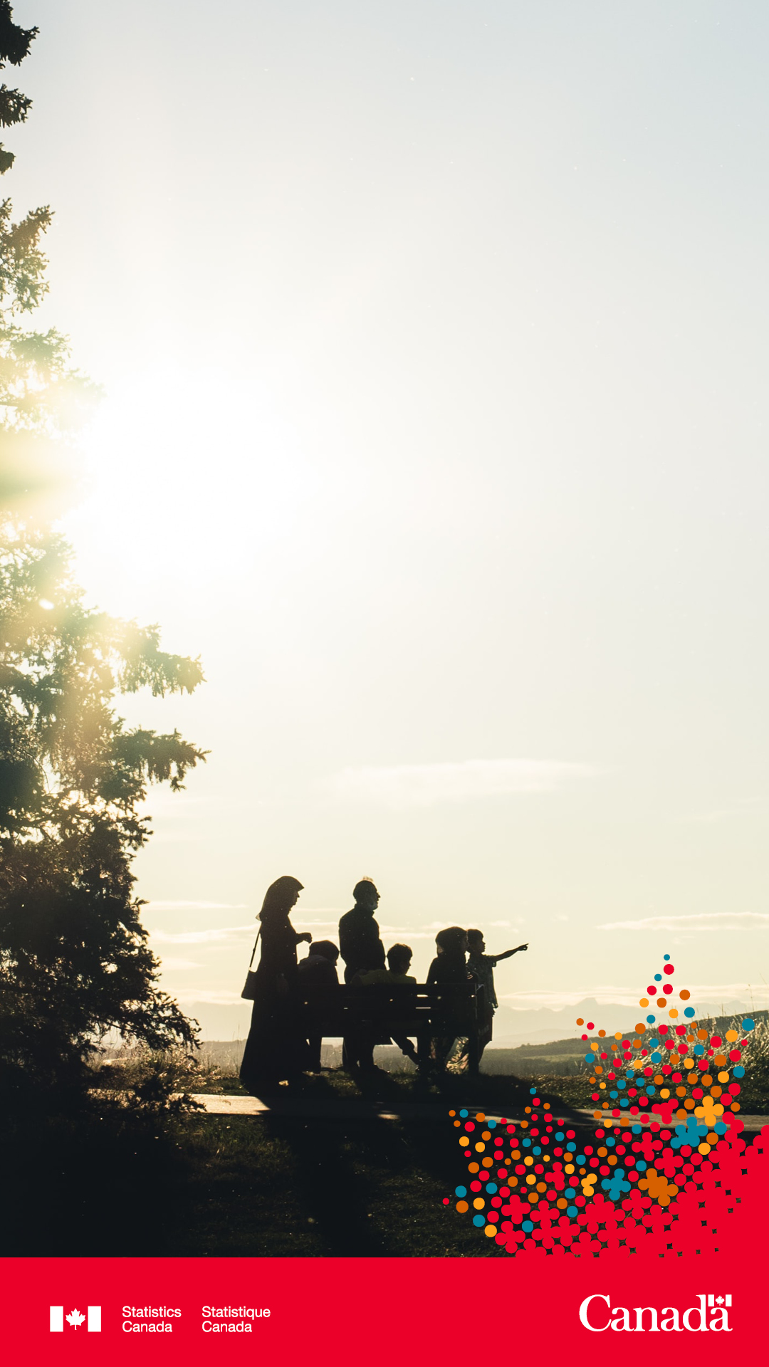 A family standing beside a tree while the sun sets