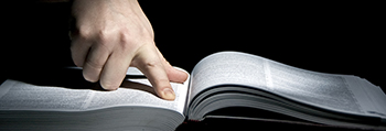 Image d’un doigt qui cherche dans un livre ouvert.
